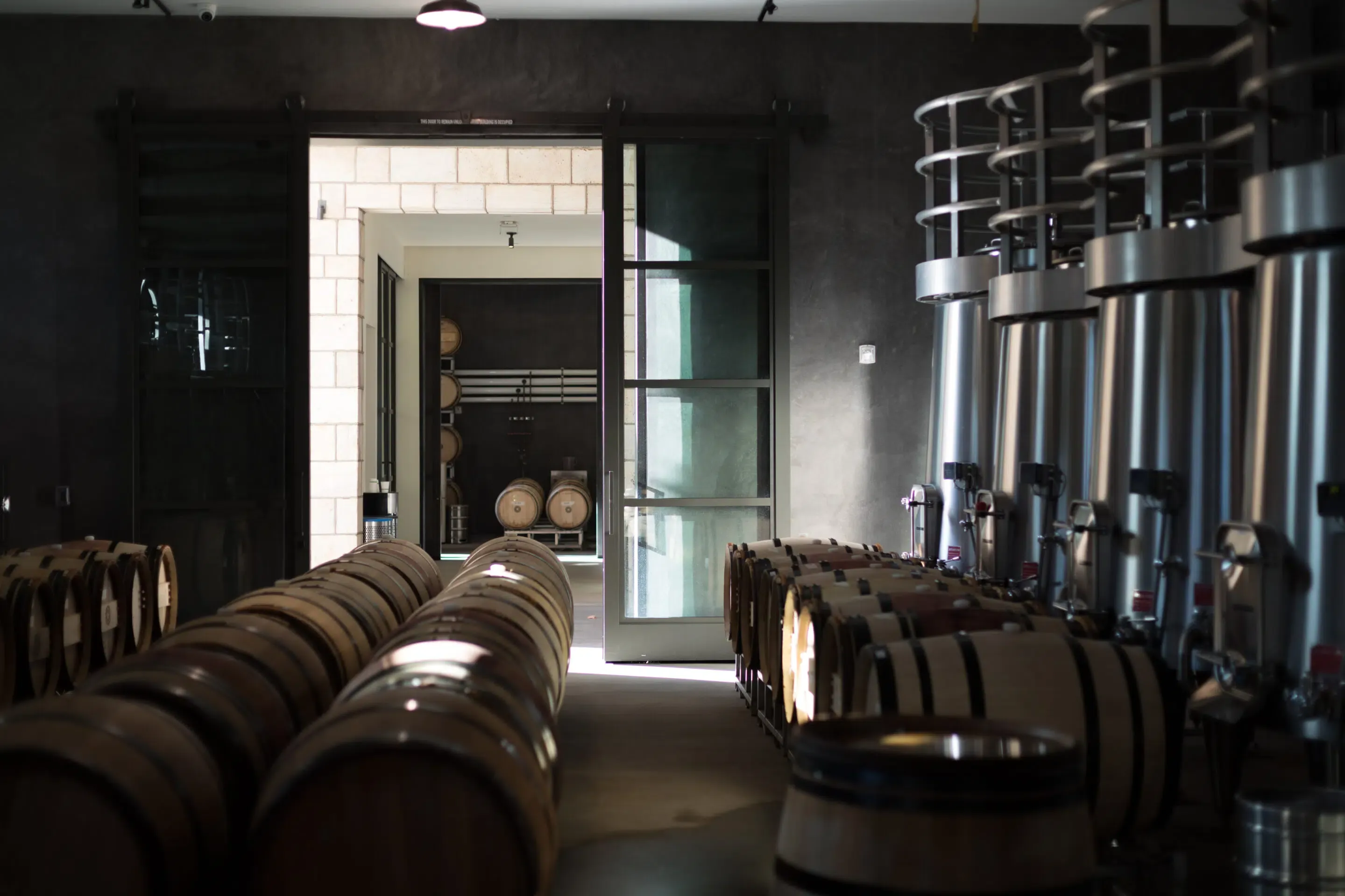 Wine cellar at Marciano Estate in Napa Valley featuring oak barrels and stainless steel tanks for artisanal winemaking.